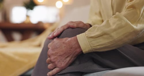 Hands, sofa and senior man with knee pain, injury or muscle sprain in living room at nursing home