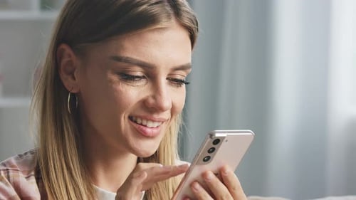 Smiling Woman Using a Mobile Phone Indoors