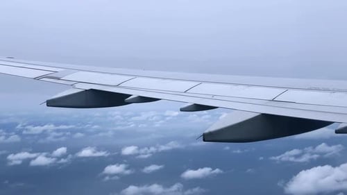 Vue depuis une aile d'avion survolant des nuages avec un ciel lumineux en arrière-plan