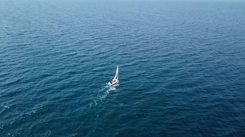 Aerial follow footage of a small Sail Boat sailing slowly at sea