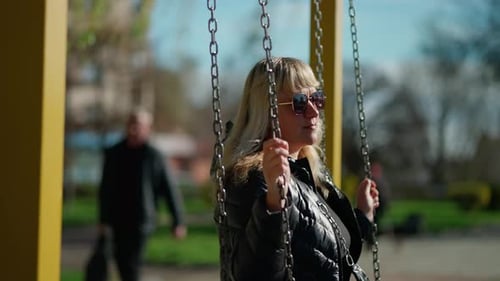 Woman Relaxes on Swing in City Park