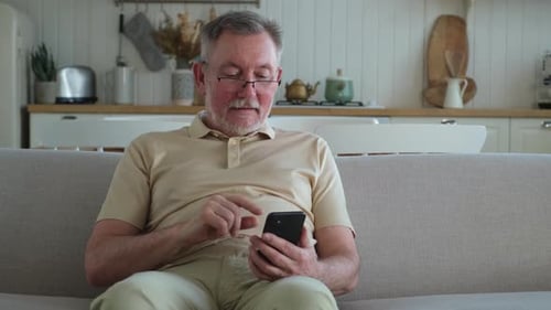 Man Using Smartphone on Couch in Home Setting