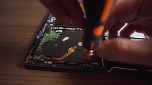 Man Unscrews and Removes Hard Drive from Laptop using Hands and Screwdriver
