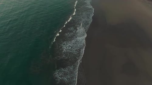 Aerial reveal flight of waves breaking on tropical Costa Rica beach in sunset