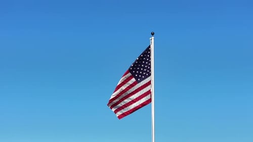American flag waving against a clear blue sky
