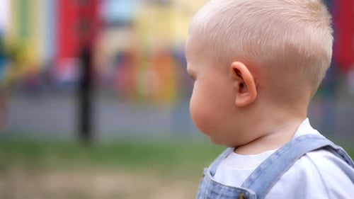 Charming blond baby boy with cute plump cheeks. Adorable Caucasian toddler turns around to look back