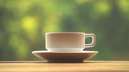 Dampfende weiße Kaffeetasse vor einem wunderschönen grünen Naturhintergrund