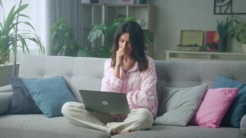 Woman Using Laptop on Sofa in Bright Living Room