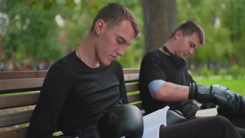 Boxers Reviewing Notes on Park Bench after Training