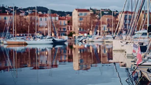 Blurred view of boats lined up along a waterfront with colorful residential buildings behind them