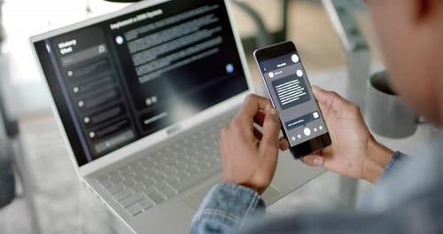 Empresário afro-americano usando smartphone e laptop com chatbot ai em casa, câmera lenta