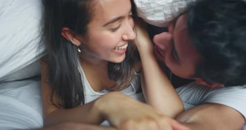 Close-up em câmera lenta de um jovem casal recém-casado vestindo pijama se divertindo e se beijando na praia