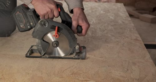 A Worker Uses a Circular Saw to Cut Plywood
