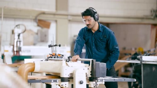 Professional Carpenter Planing Wood Board in Workshop