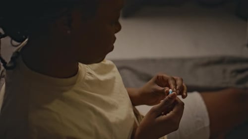 Woman Examining Pills in Dimly Lit Bedroom