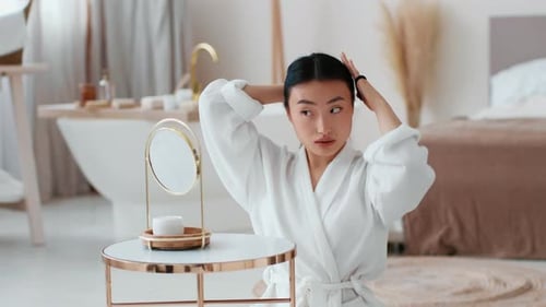 Woman in Bathrobe Puts Hair Up in Bathroom