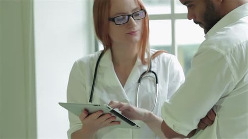 Female Doctor Showing Tablet to Patient in Clinic