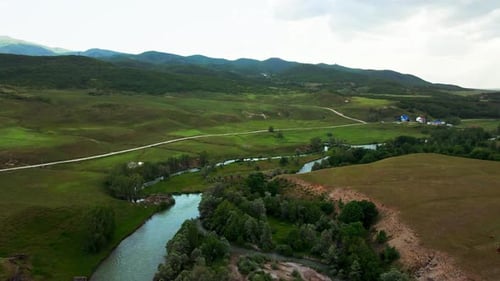 A large, lush green field with a dirt road running through it