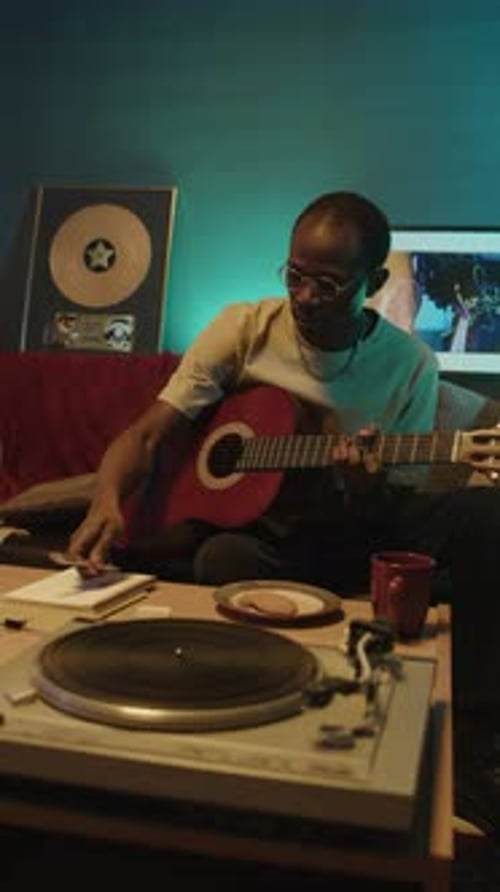 Man Plays Guitar and Writes Song at Night