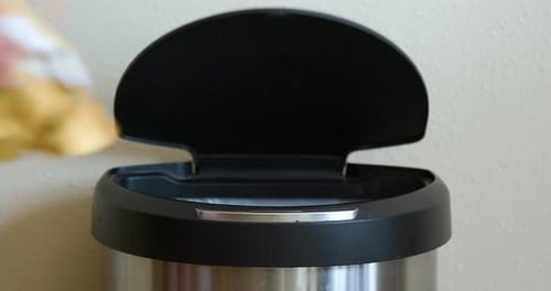 Man Throws Away Yellow Package in Motion Sensing Touchless Trash Can - Close-Up