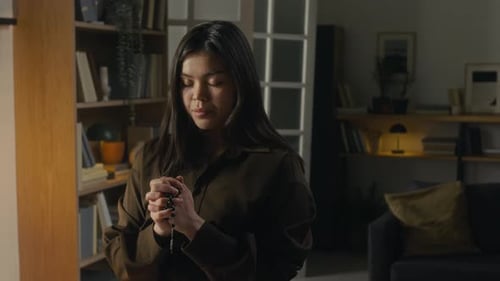 Woman with Rosary Praying in Living Room