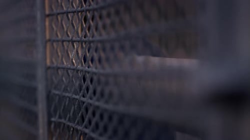 Fence Mesh Netting at Sunset Close Up. Metallic Grid Surface Construction. Wire