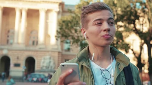 Close Up Face Handsome Young Man Use Phone Speak on Mobile in Headphone Look Around Walk Standing on