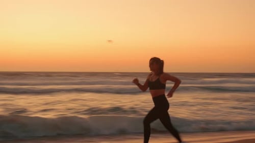 Determined Jogger Woman Running on Sandy Shore During Sunset at Beach