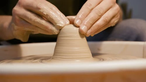 Potter shaping clay on spinning wheel, craft