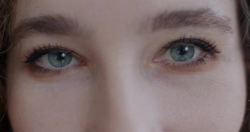 Closeup Slow Motion Portrait of Young Woman Looking at Camera with Green Eyes Indoors