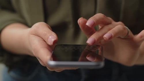 A Woman Holds a Smartphone in Her Hand and Quickly Types a Message Cropped View of Woman Using