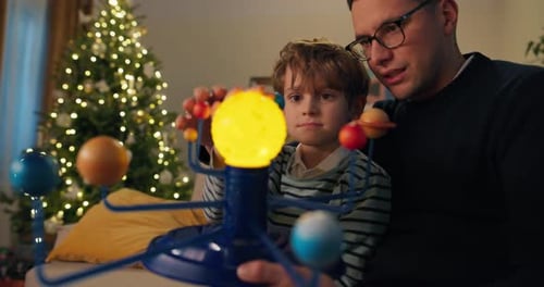 Father and Son Playing with Solar System Model