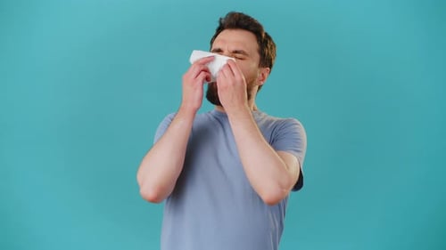Man Sneezing and Has Sore Throat Against Blue