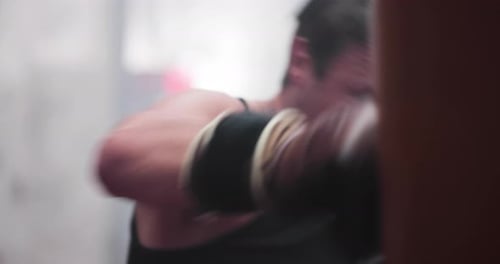 Determined Man Boxing Punching Bag in Gym