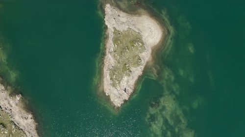 Aerial top down view of blue and green lake on Grimselpass in the Swiss alps, slowly flying upwards.