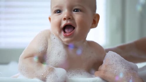 Happy Baby Bathed in Soap Bubbles at Home