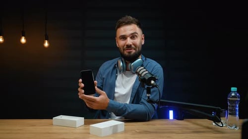 Young Man Talking About Phone Review At Desk