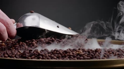 Hot Roasted Coffee Seeds Scooping Using Metal Ladle Close Up. Unknown Man