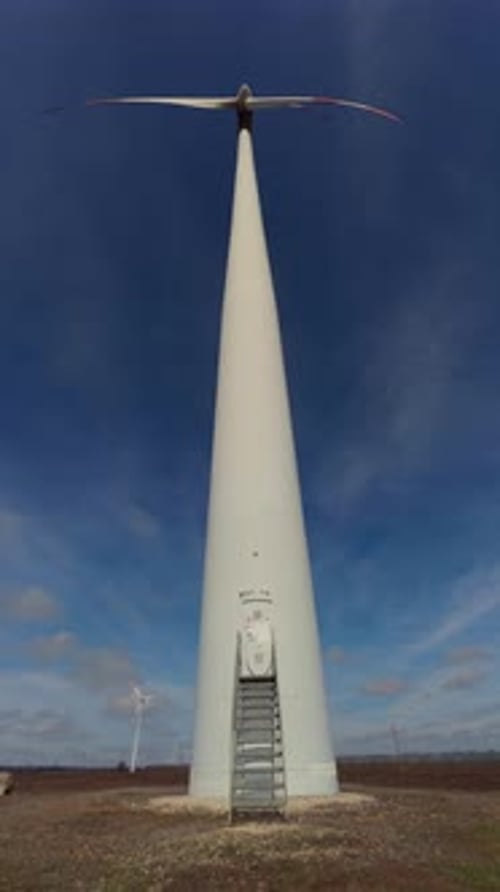 Giant Wind Turbine in a Field Under Blue Sky with Wispy Clouds