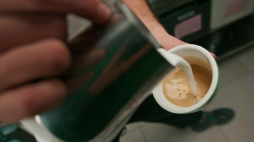 Barista making latte art in a cafe Male hands pouring steam of milk into a cup of Cappuccino