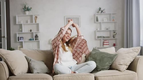 Cheerful Woman Dancing on a Beige Sofa