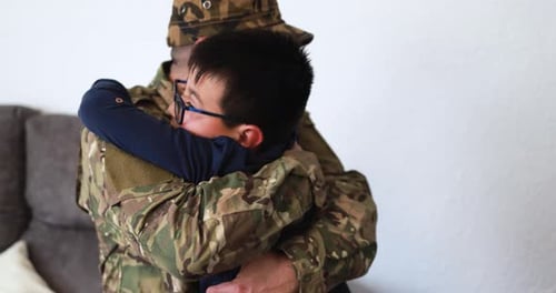Boy Embracing Man in Military Uniform Indoors