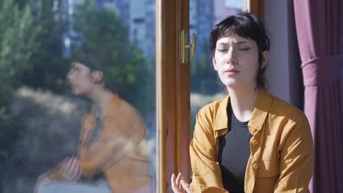 Une jeune femme malade regarde par la fenêtre pour se détendre.