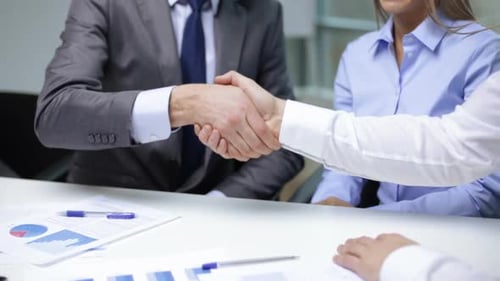 Business Handshake at Corporate Office with Financial Documents