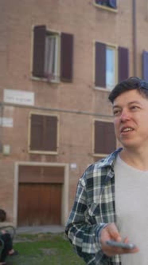 A Person is Seen Using a Smartphone Outdoors in an Urban Setting Next to a Building