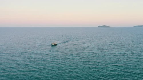Fishing Boat Sailing on Ocean at Sunrise
