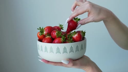 Hand Reaching for Fresh Strawberries in Bowl