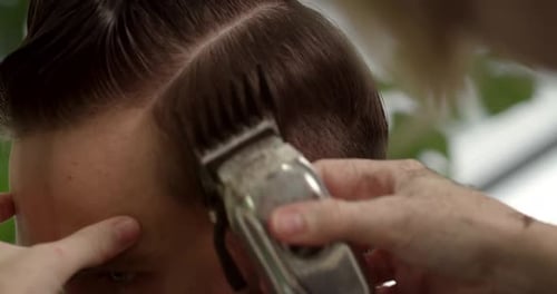Friseur macht eine Frisur mit einem Haarkamm und einer Haarmaschine Stylischer Herrenfriseursalon