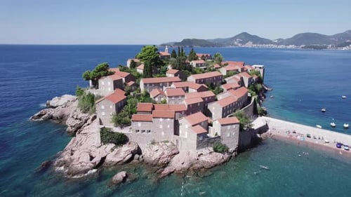 Eine Drohne fliegt an einem sonnigen Tag in Montenegro über die Insel Sveti Stefan
