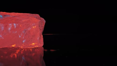 Crystal clear quartz under warm orange studio light on black background, smooth pan reveals reflecti